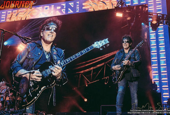 Neal Schon Journey Founder Playing Guitar under a Journey Banner